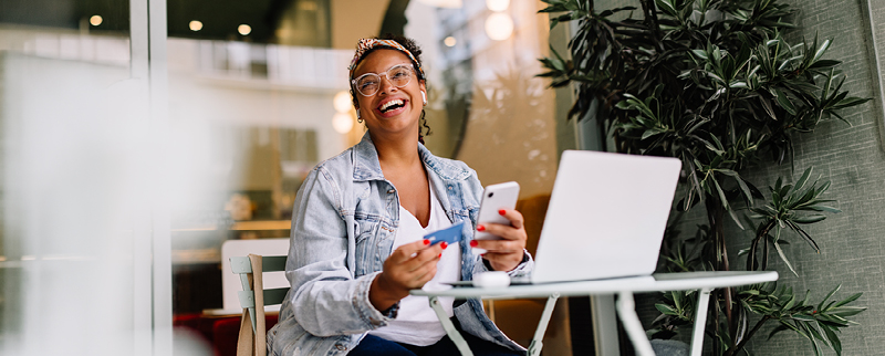 woman sitting in cafe with laptop and credit card