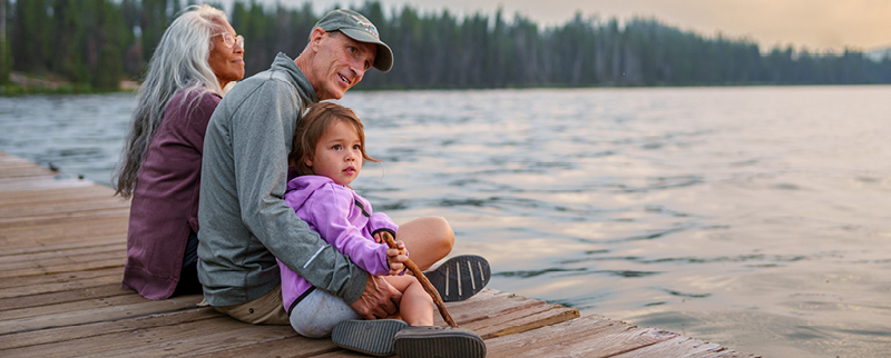 family enjoying a sunset on a lake dock