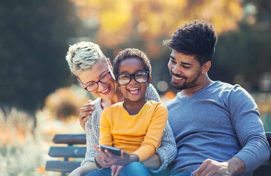 parents sitting with child on park bench