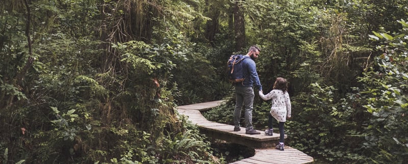 father guiding daughter on boardwalk